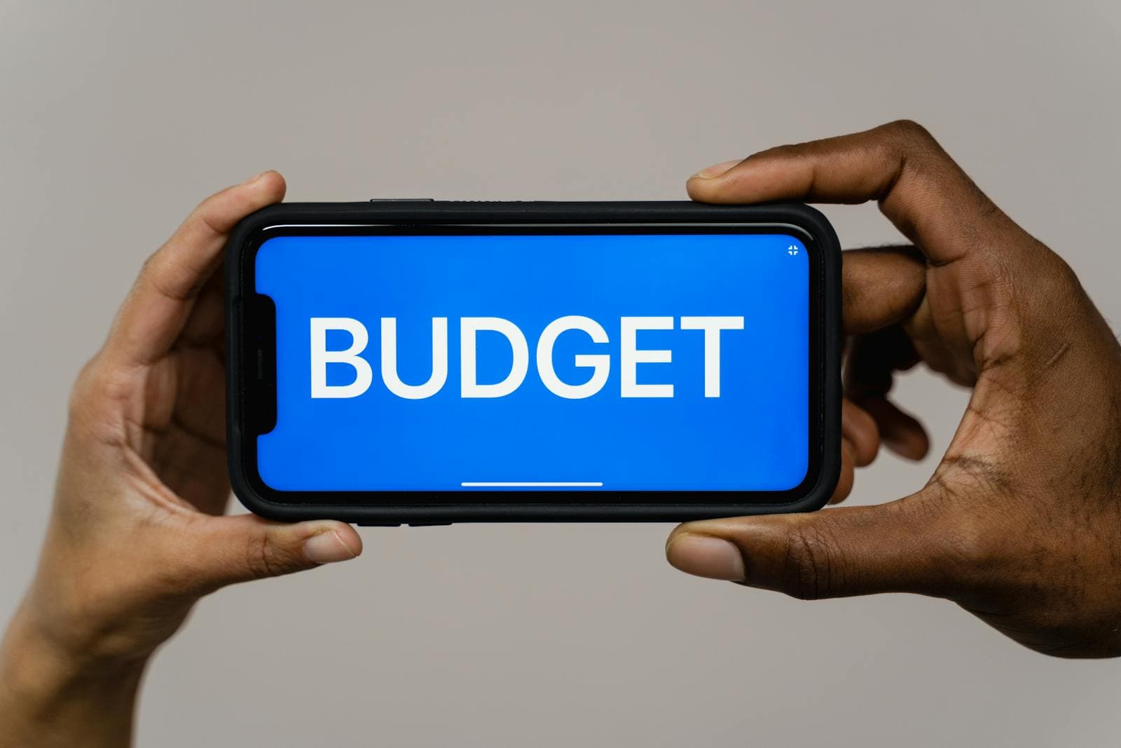 Hands holding a smartphone with a budgeting screen, representing the moment when product guidance needs to feel clear and actionable.